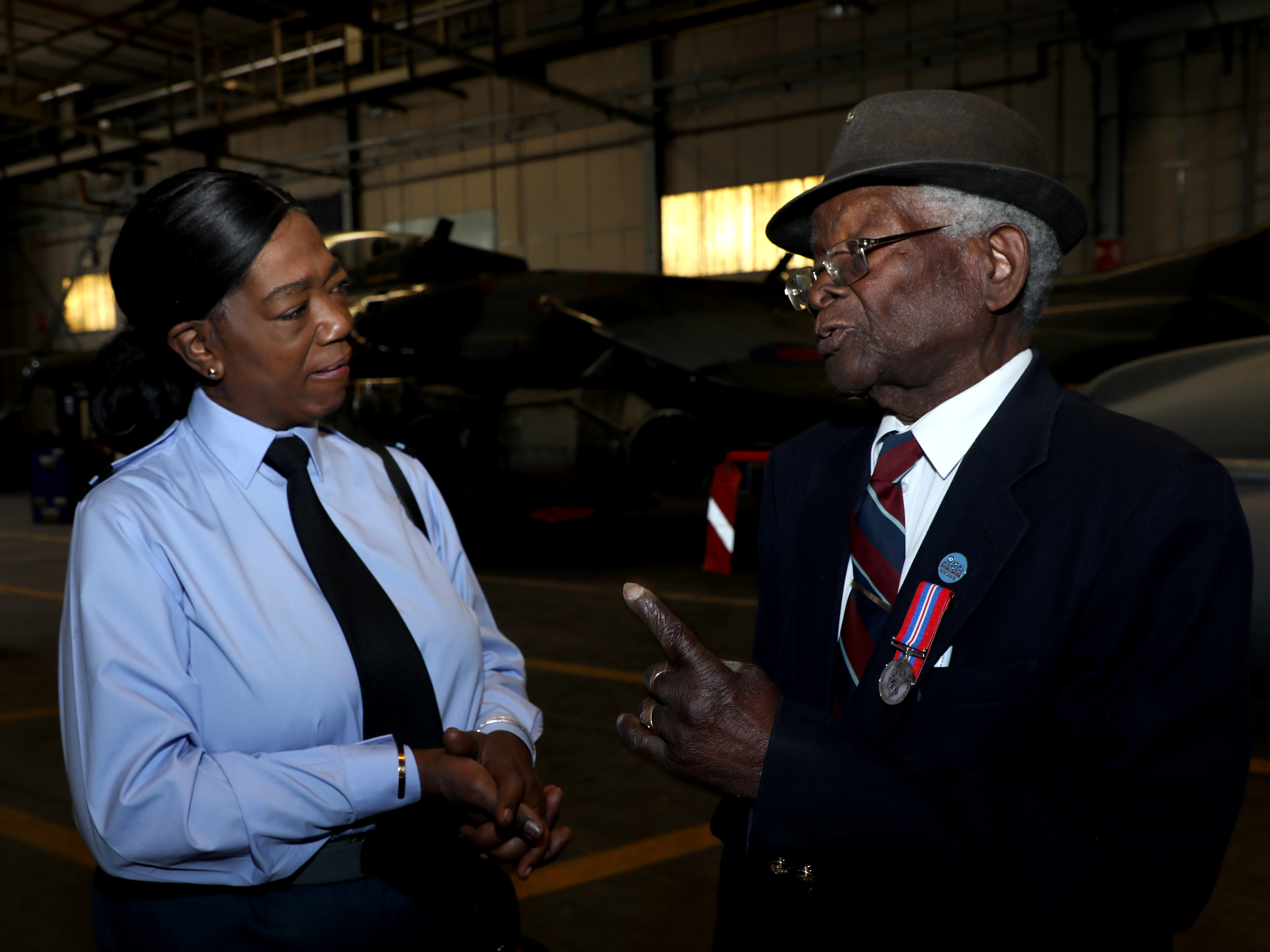Image shows veteran and RAF aviator talking inside a hangar.